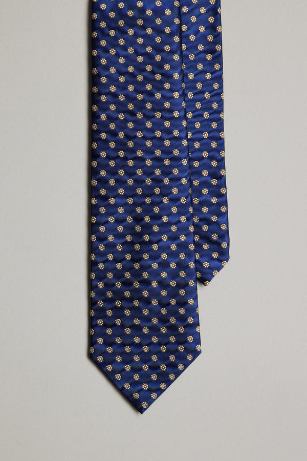 The Barkers Rendale Flower Tie features a navy silk base with repeating small yellow and white floral motifs, elegantly displayed against a plain light background.