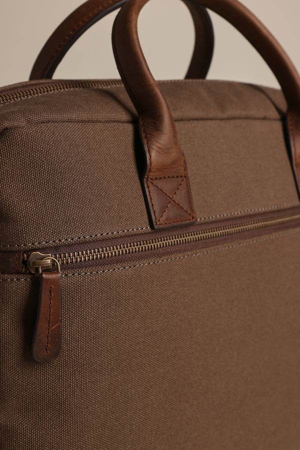 Close-up of the Barkers Redford Canvas Laptop Bag, featuring premium leather handles, a zippered pocket with a leather pull tab, and visible stitching on both the bag and handles.