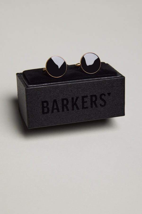 The Barkers Gold and Black Round Cufflink is shown on a black velvet holder atop a Barkers box, all set against a plain light gray background.