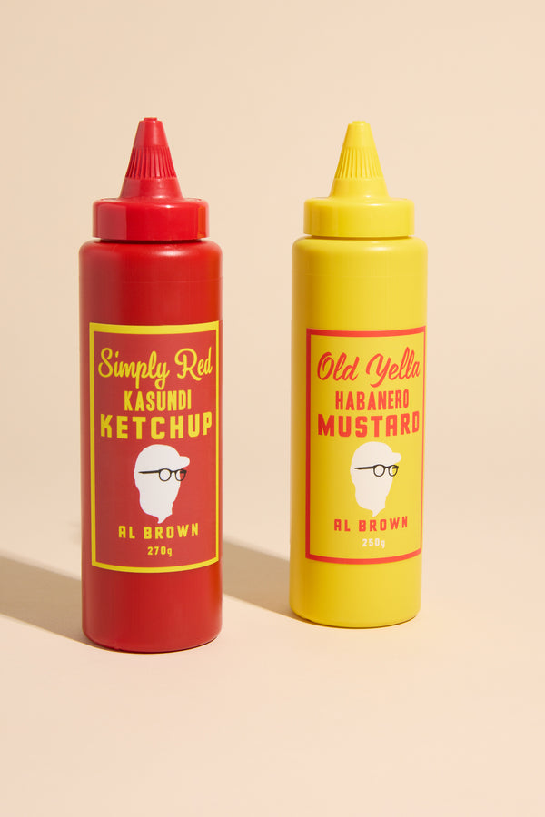 Two Al's Old Yella & Simply Red Sauce Caddy bottles stand side by side on a beige background: one is Simply Red Kasundi Ketchup, the other Old Yella Habanero Mustard.