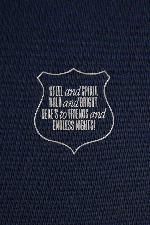 A dark blue background with a white outlined badge reads: STEEL and SPIRIT, BOLD and BRIGHT, HERE’S to FRIENDS and ENDLESS NIGHTS!—the perfect toast for Barkers’ The Essentials Hip Flask gift box.