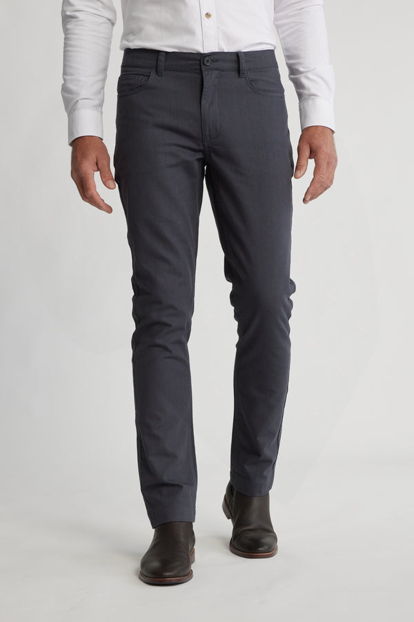 A man stands against a plain light background wearing Barkers Oxmor 5 Pkt Pant O trousers, a white dress shirt, and dark brown dress boots. His face is not visible.