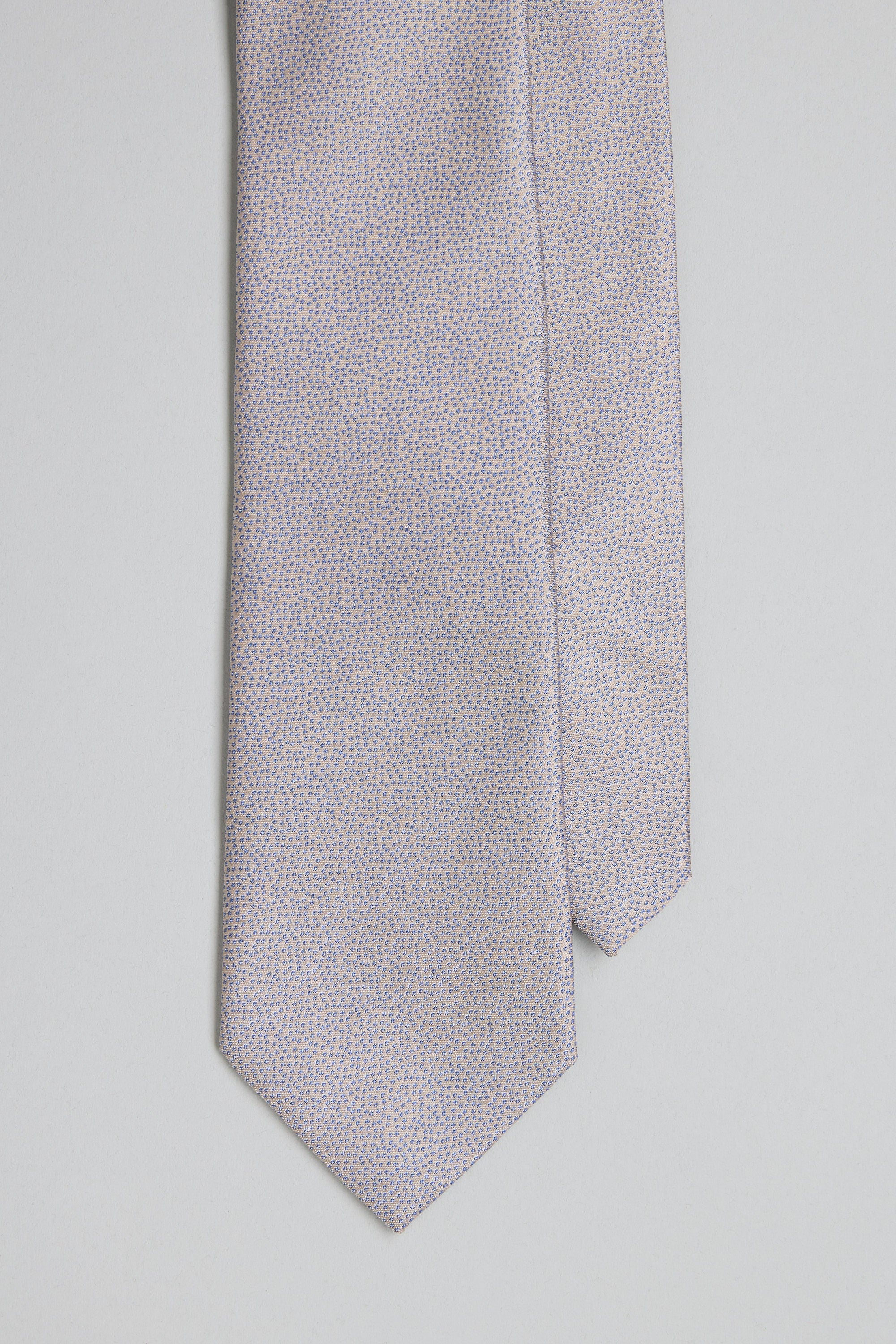 A close-up of the Barkers Empire Texture Tie, a light silk accessory featuring a subtle blue dot jacquard on a pale background—ideal for elevating business attire, shown against a neutral surface.