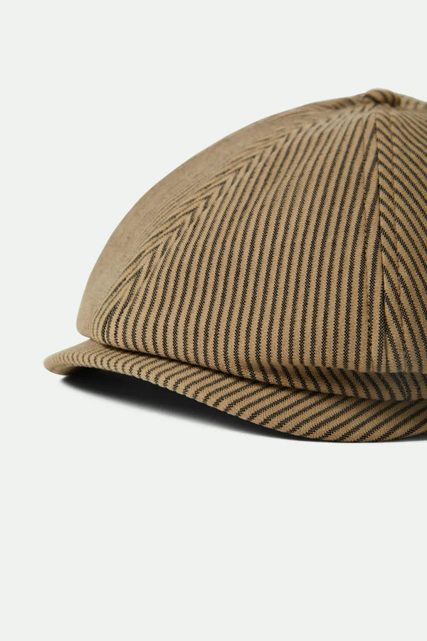 A close-up of the Brixton Brood Snap cap by Brixton, featuring a brown and black herringbone pattern and curved brim, highlights its vintage style against a plain white background.