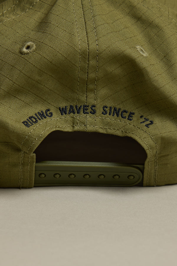 Close-up of the back of a Barkers Longboard Cap in olive green. Features an adjustable snapback and "RIDING WAVES SINCE 72" embroidered above the opening in dark blue. A stylish and secure fit from Barkers.
