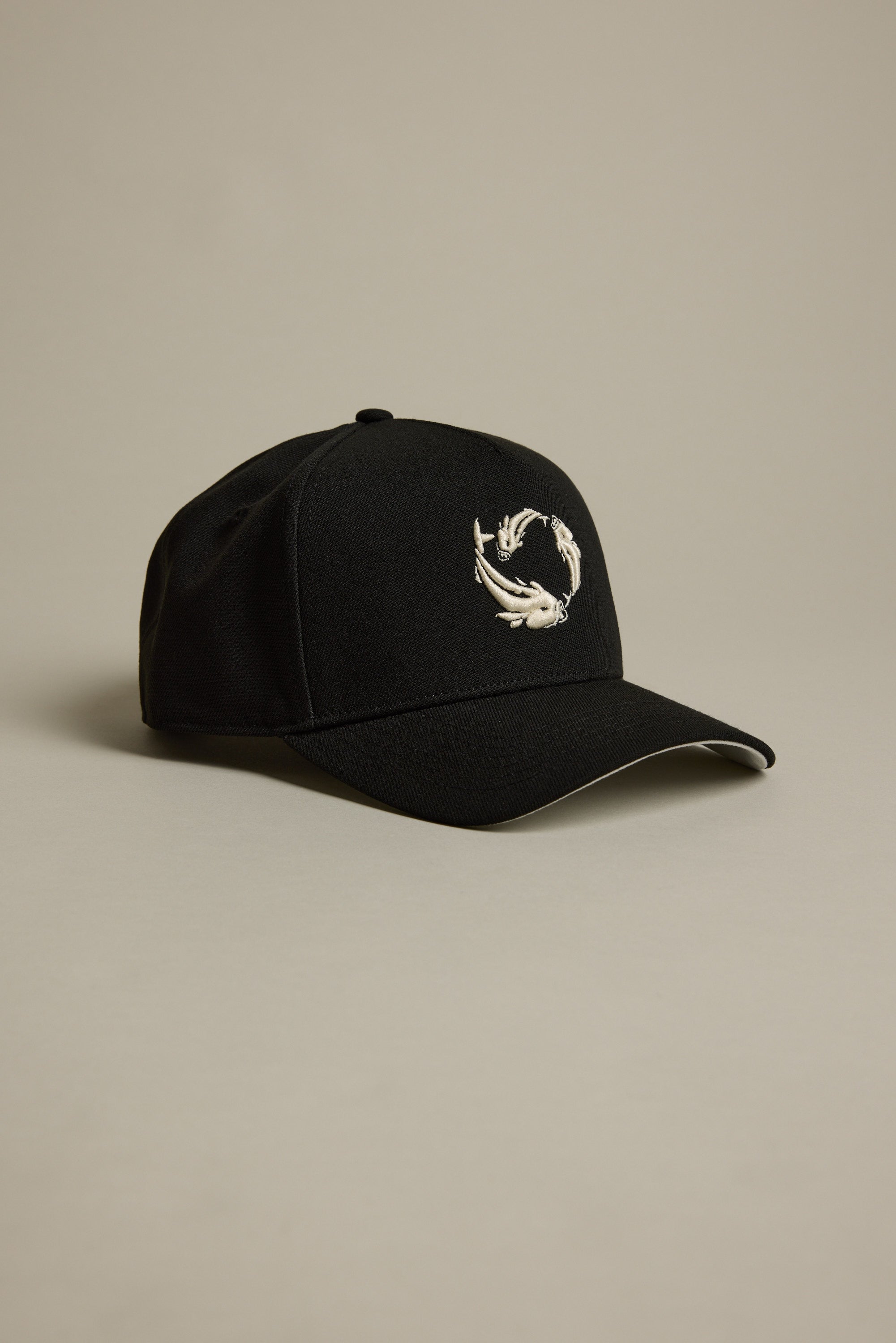 The Legasea Logo Snapback Cap by Legasea features a black design with a white embroidered koi fish logo on the front, displayed on a beige background. This limited edition cap makes a unique addition to any collection.