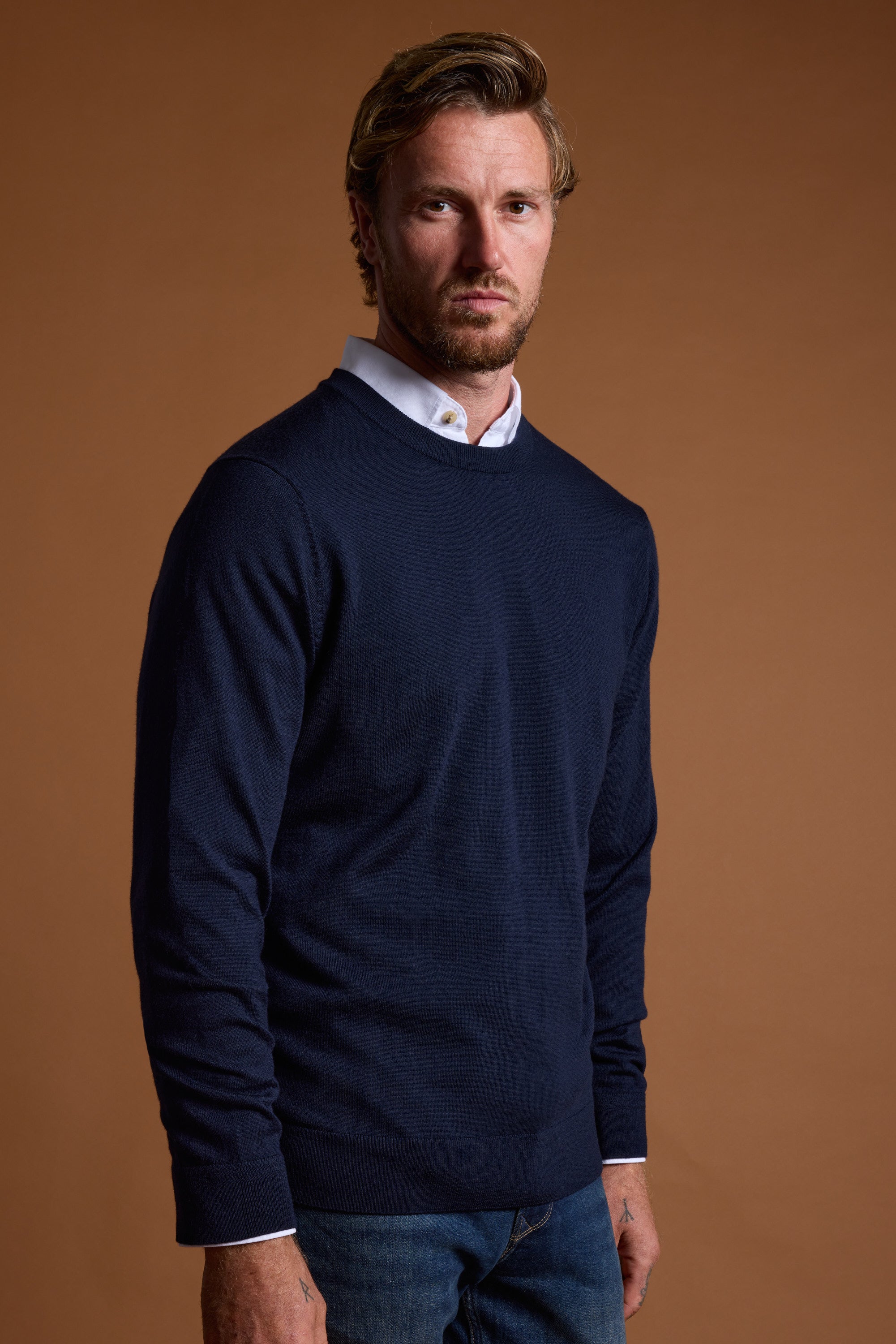Man in Barkers Skyland ZQrx Merino Crew stands against a plain brown background.