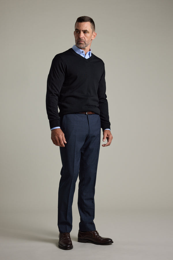 Man wearing Barkers Skyland ZQrx Merino Vee, blue shirt, dress pants, and brown shoes indoors.