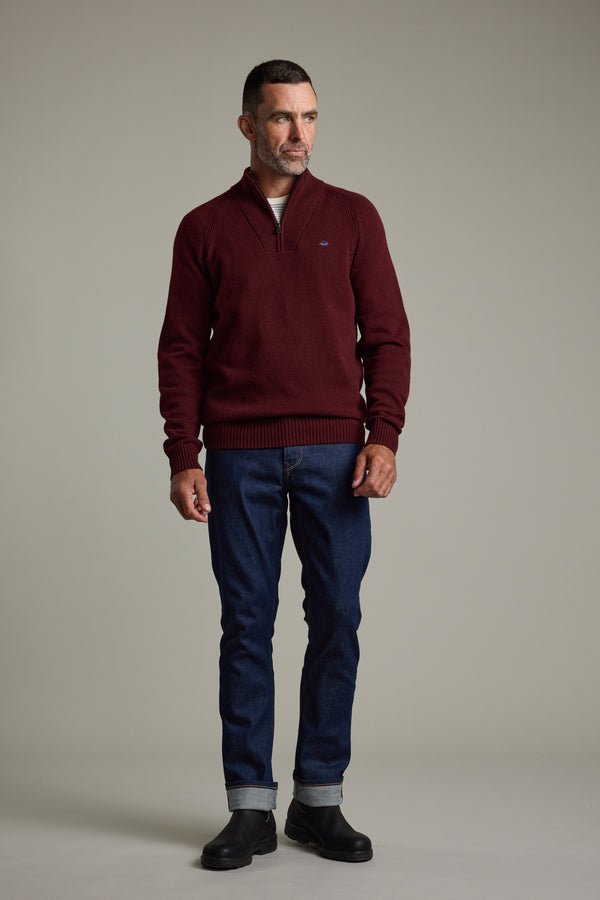 Man in a Barkers Rowley Woollen 1/4 Zip, blue jeans, and black boots on a plain background.