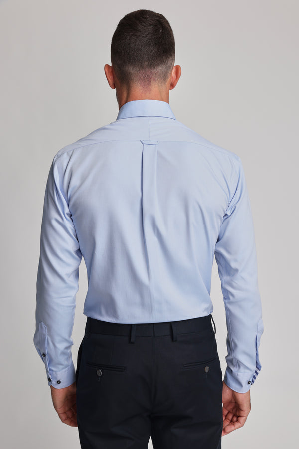 A man, with his back to the camera, wears a Barkers Verona Shirt in light blue and black dress pants against a plain light backdrop.
