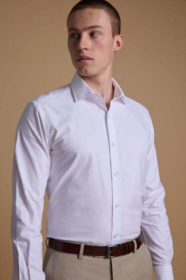 Man in Barkers Aster Texture Business Shirt and beige pants looks to the side against beige.