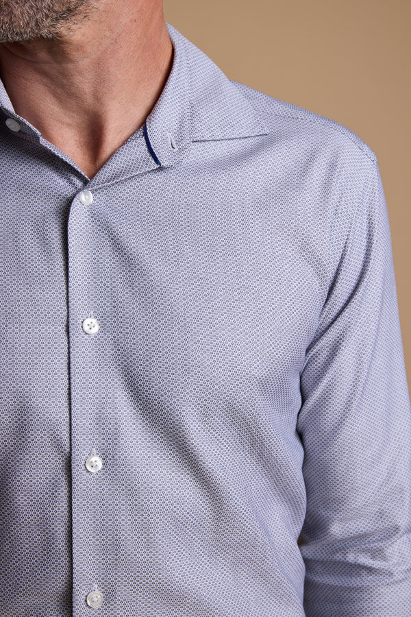 A close-up shows a man in the Barkers Eaton Jacquard Business Shirt, featuring a light blue pattern and spread collar. The shot, cropped at the mouth and mid-torso, is set against a plain beige background.