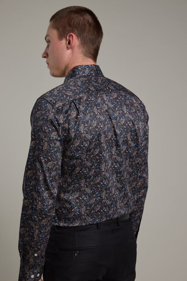 A man is seen from behind wearing the Barkers Hilton Print Shirt, a long-sleeved, dark floral design paired with black pants. The tailored fit stands out against a plain, neutral background.