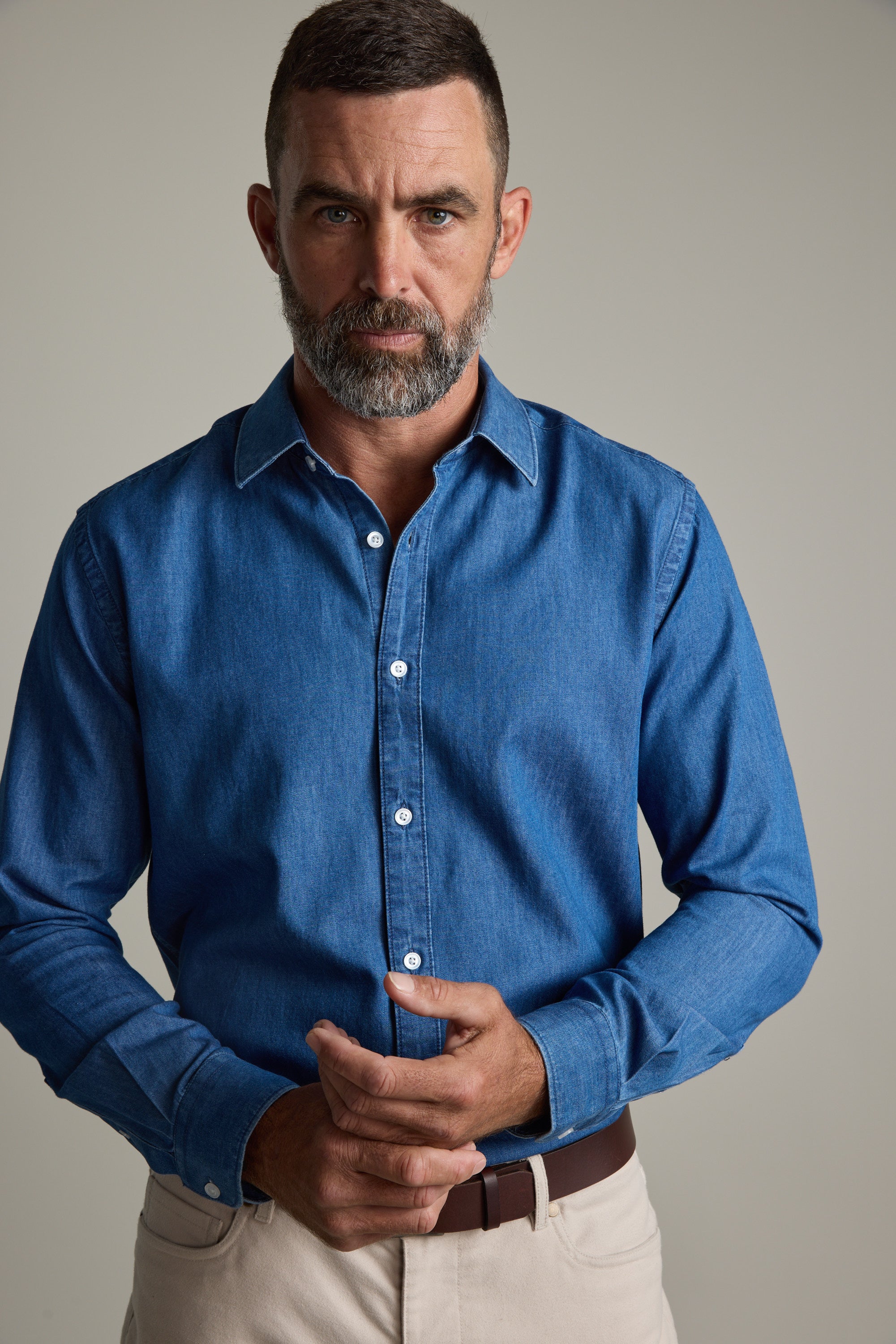 Man with a beard wears Barkers' Wyatt Denim Business Shirt and beige pants against plain background.