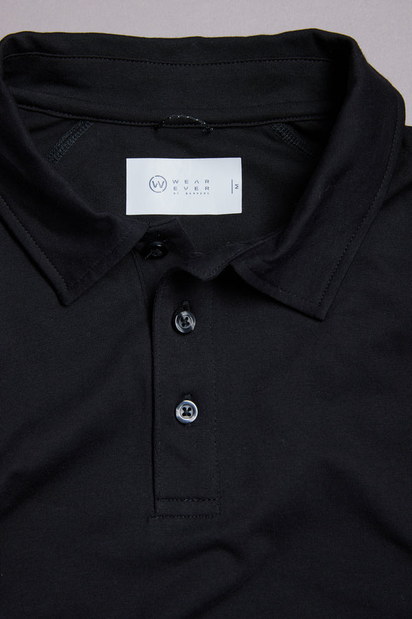 A close-up of the WearEver Outbound Polo in black, showcasing its collar, two buttons, and inner white label with WearEver branding and size info. Made from a breathable cotton-blend for lightweight stretch and all-day comfort.