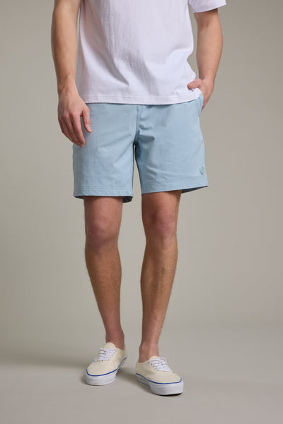A person wearing a white t-shirt, Barkers Davis Weekend Short in light blue, and white sneakers stands with one hand in their pocket against a neutral background. Their face is not visible.