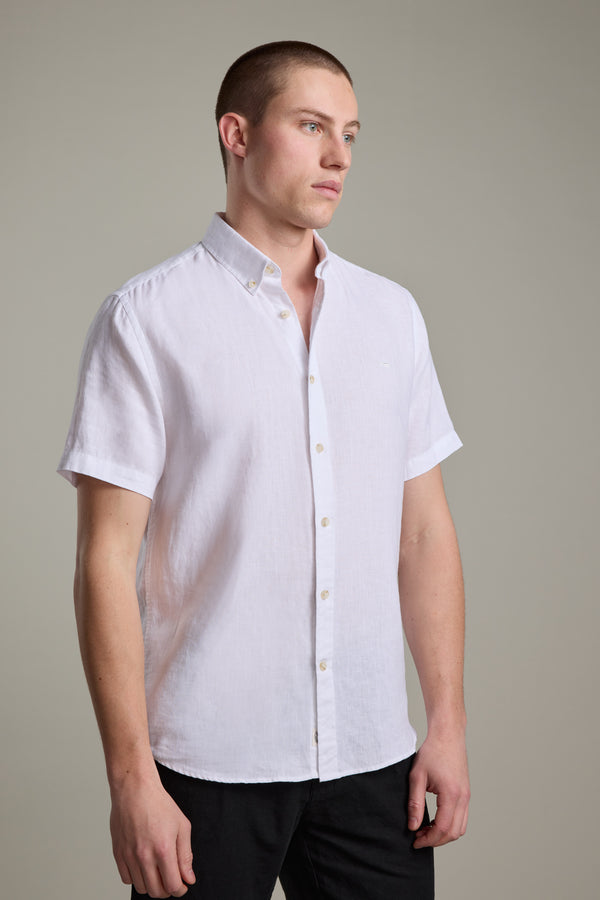 Man in a white Barkers Gentry Linen Shirt and black pants against a plain background.