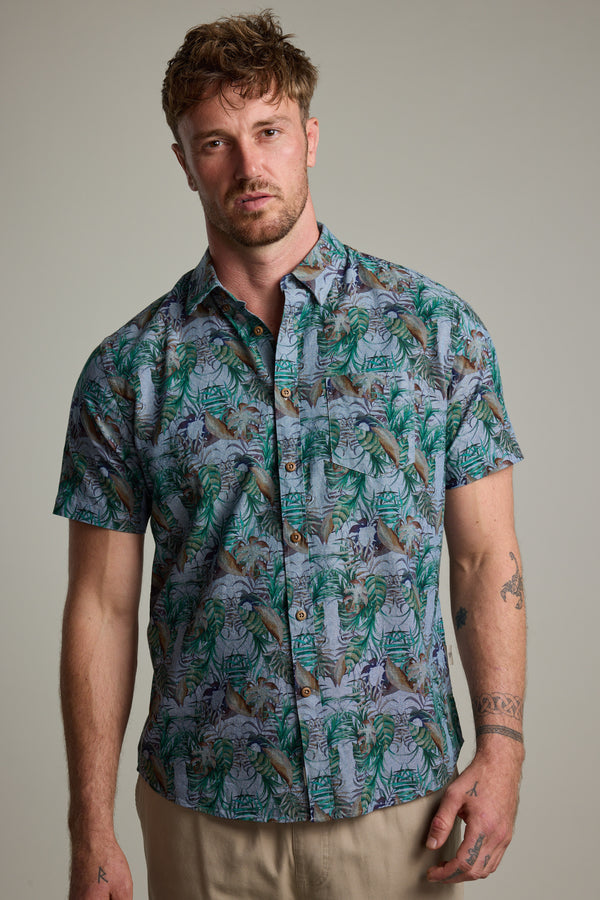 A man with short, tousled hair wears the Barkers Rockport Print Shirt—a short-sleeve tropical print style—with beige pants. He faces the camera with a neutral expression against a plain background.