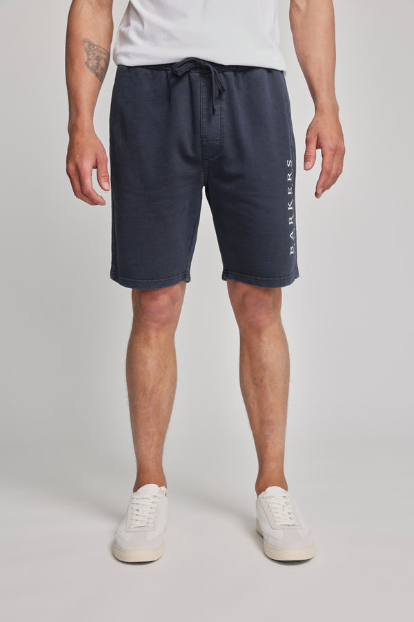 A man wearing Barkers Organic Classic Print Track Shorts and white shoes.