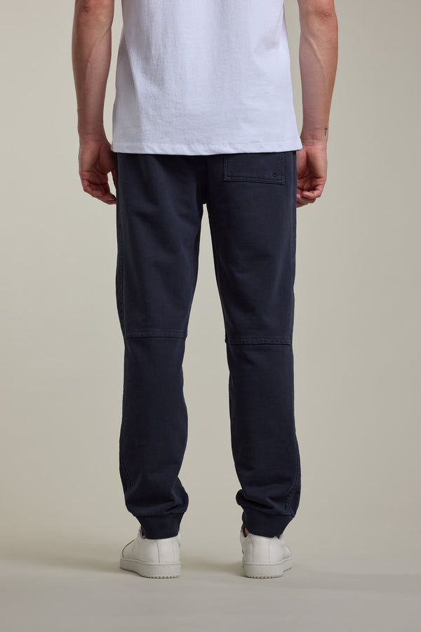 Person wearing a white t-shirt, Barkers Organic Classic Print Track Pant, and white shoes, back view.