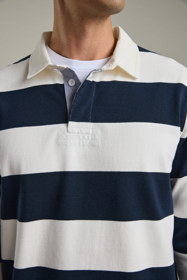 Wearing Barkers’ Provincial Long Sleeve Rugby Jersey in navy and white stripes with a white collar.