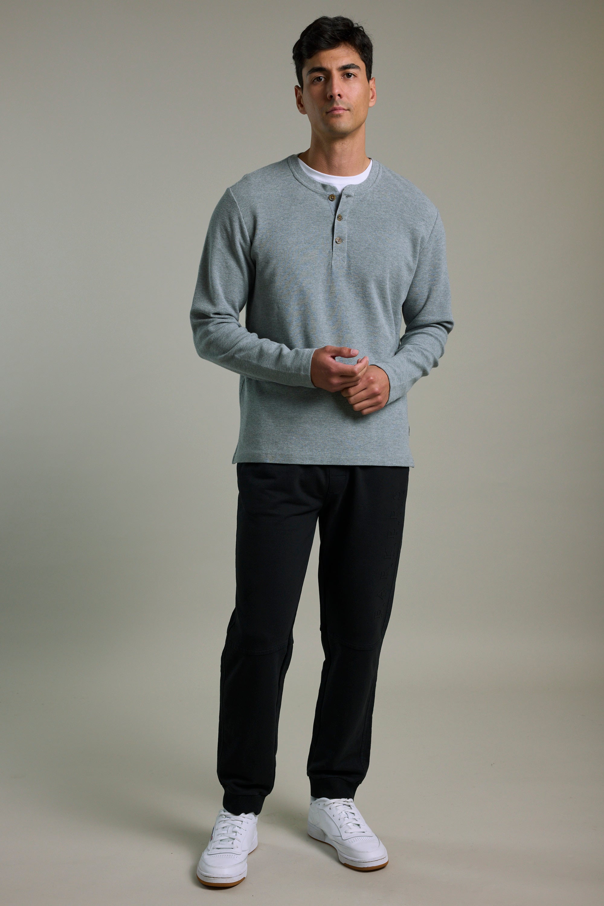 Man in a gray henley, Barkers Organic Classic Print Track Pant, and white sneakers.