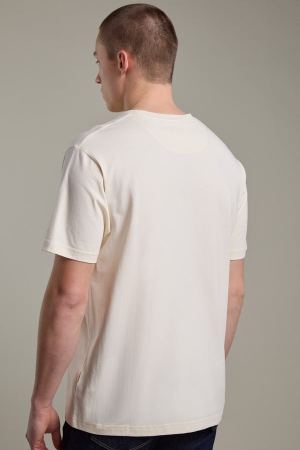 A person with short hair, seen from behind, wears a Barkers Boardriders Logo Tee in off-white and dark pants against a neutral background.