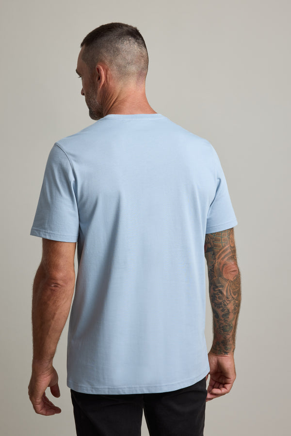 Man with short hair wears Barkers Good Earth Cotton Essential Tee in light blue, seen from back.