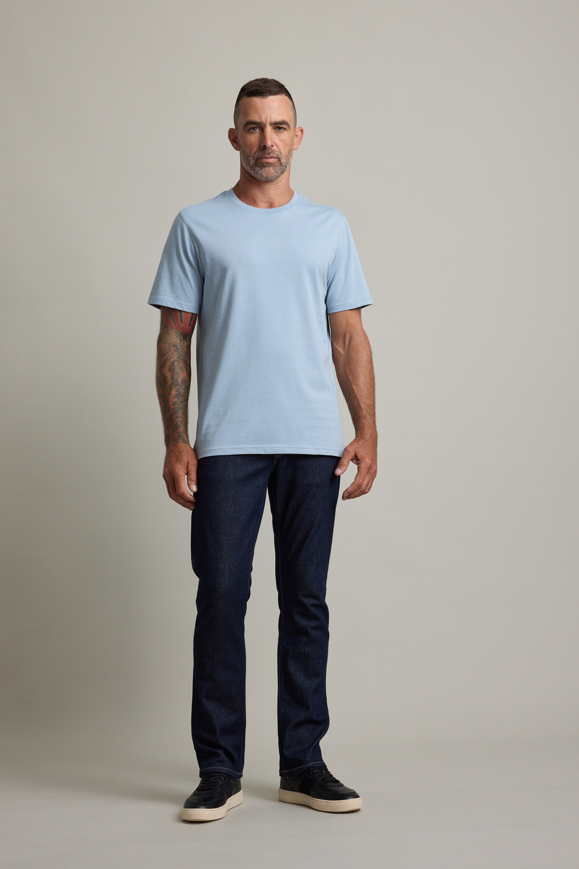 Man in a light blue Barkers Good Earth Cotton Essential Tee and dark jeans on a plain background.