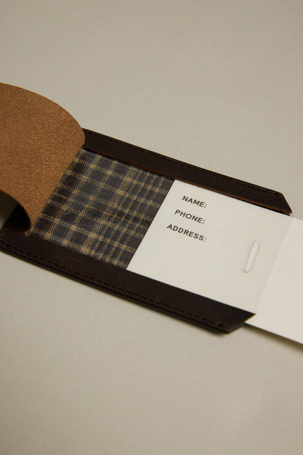 The Barkers Voyage Leather Luggage Tag features a brown leather exterior, plaid fabric lining, and a white card for your contact info—an ideal stylish travel accessory or corporate gift, shown open on a plain surface.