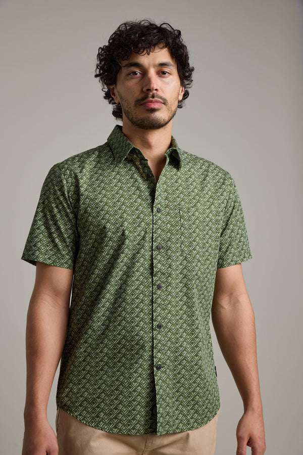 A man with curly dark hair and a short beard wears the Barkers Oxnard Print Shirt in green and beige pants, standing against a plain light background.