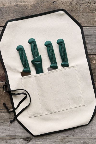 The IronClad Ghost Knife Roll is a limited edition white canvas roll, shown open on wood, with four green-handled knives partly visible in separate pockets.