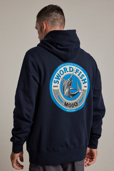 A man wearing a dark Swordfish Mojo Logo Hoody made from responsibly sourced cotton stands with his back to the camera, displaying the Swordfish Mojo brand’s large circular logo featuring a jumping swordfish and blue accents since 2001.