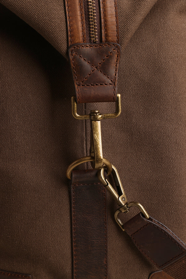 Close-up of the Barkers Newman Canvas Weekender, showing its brown canvas, leather strap with brass clasp and hardware, and detailed stitching. The texture and craftsmanship of this men's weekender are clearly visible.