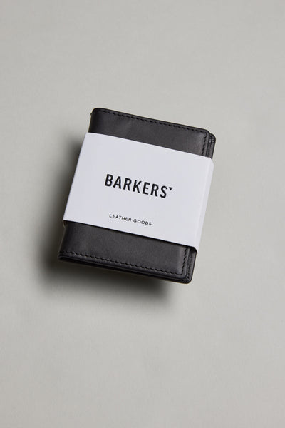 The Marlin Leather Slim Wallet by Barkers, a sustainable wallet wrapped with a white paper band labeled Barkers, is displayed on a light gray surface.