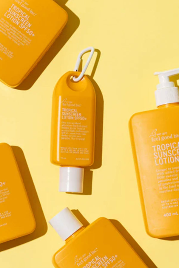 Other brand Tropical Sunscreen Lotion SPF50+ 200ml bottles, including high performance variants with white carabiners and options with pumps or flat caps, are arranged on a pastel yellow background.