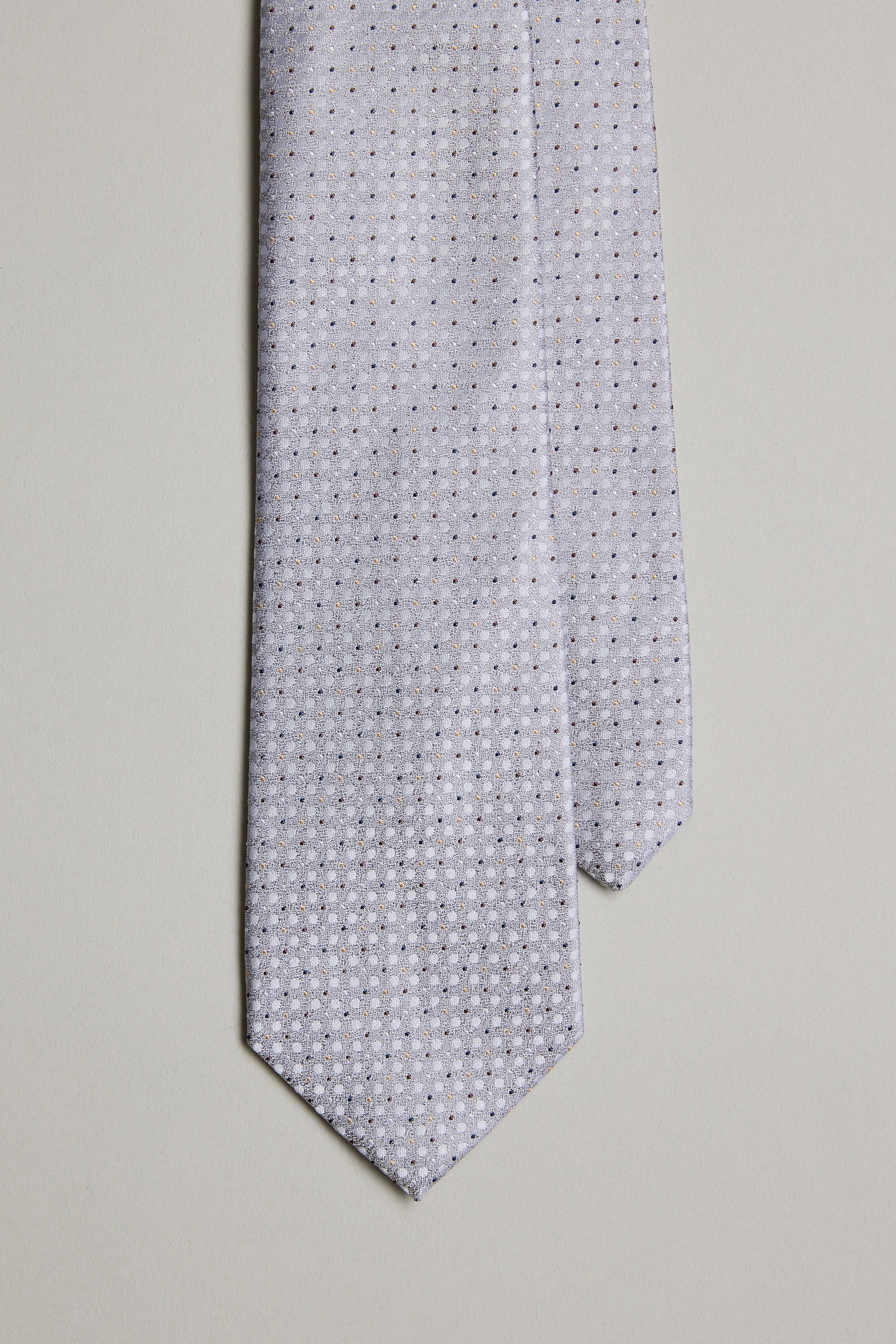 The Barkers Nilson Dot Tie, crafted from fine silk, features a light gray color with a small repeating geometric dot pattern, shown up close against a plain light background.