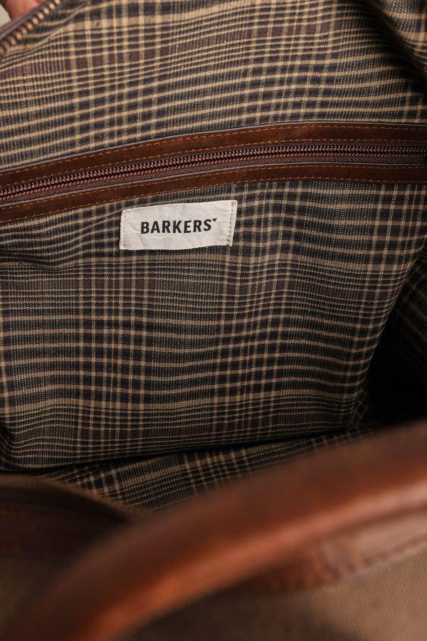 Close-up of the Barkers Newman Canvas Weekender interior, showing brown plaid lining, brown zipper, white “Barkers” fabric label, and partial brown leather trim.