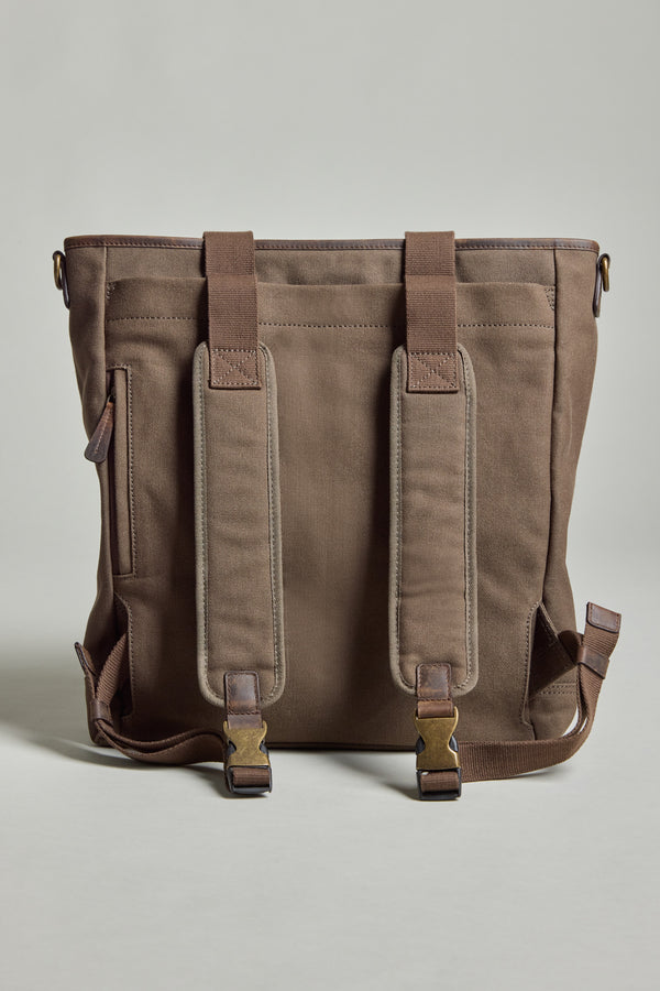 The Barkers Foxton Canvas Convertible Tote, a brown cotton canvas bag with leather accents, metal buckles, and two padded shoulder straps, is shown standing upright against a plain light gray background.