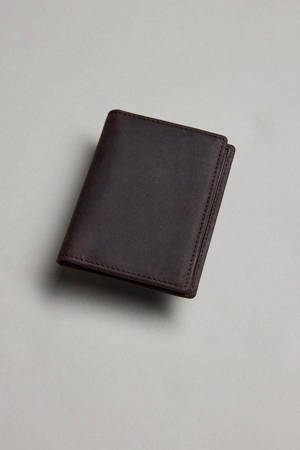 The Barkers Marlin Leather Slim Wallet, made from premium dark brown cowhide, sits closed on a light gray surface with soft lighting creating a subtle shadow.
