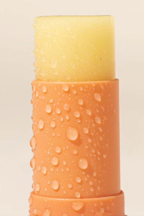 A 10ml orange tube of Other Sensitive Lip Balm SPF50+ with water droplets on its surface.