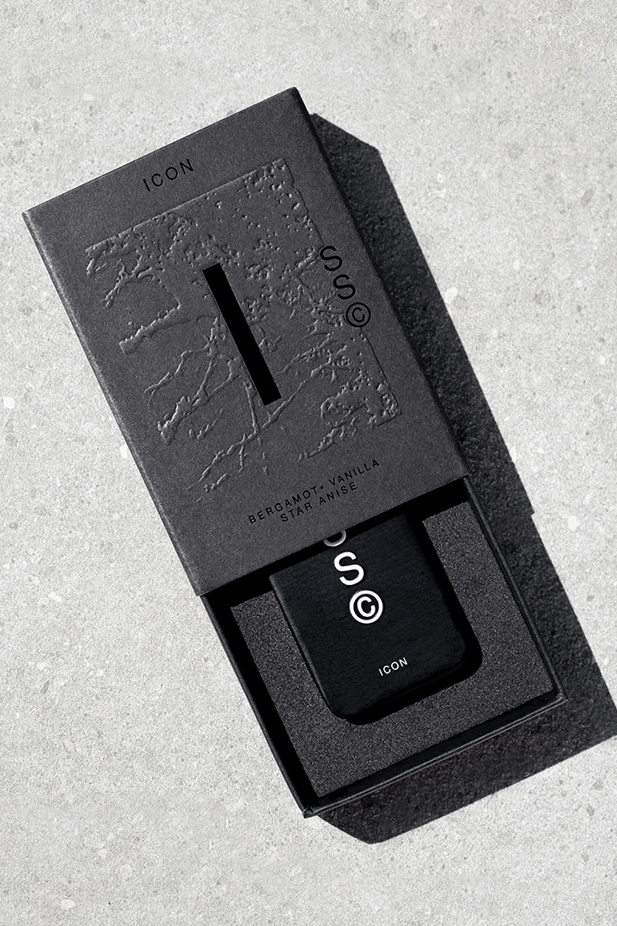A black rectangular Solid State - Icon perfume bottle with white "ICON" text is partially slid from a matching textured box, set on a light gray surface. The packaging reflects Australian scents: Bergamot • Vanilla • Star Anise.