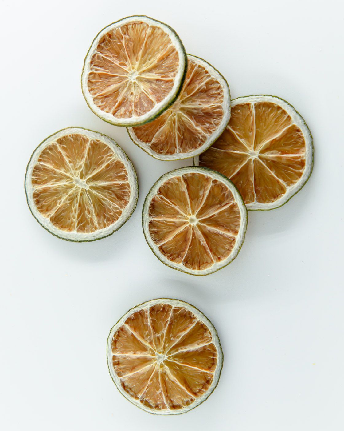 F N Lemons - Limes 10 Slice Pouch by F N Lemons features dried lime slices with brownish centers and green edges, ideal for enhancing baking or cocktail garnishes on any elegant tablescape.