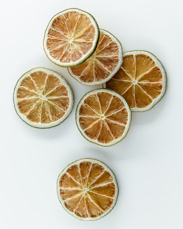 F N Lemons - Limes 10 Slice Pouch by F N Lemons features dried lime slices with brownish centers and green edges, ideal for enhancing baking or cocktail garnishes on any elegant tablescape.