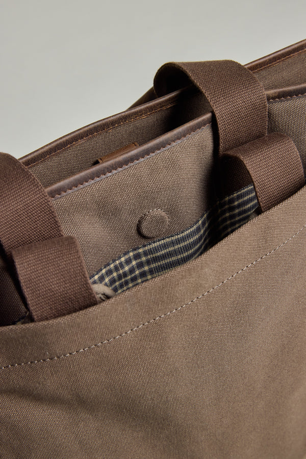Close-up of the Barkers Foxton Canvas Convertible Tote, a brown cotton bag with handles, snap button closure, and a partially visible pocket lined with checkered fabric.