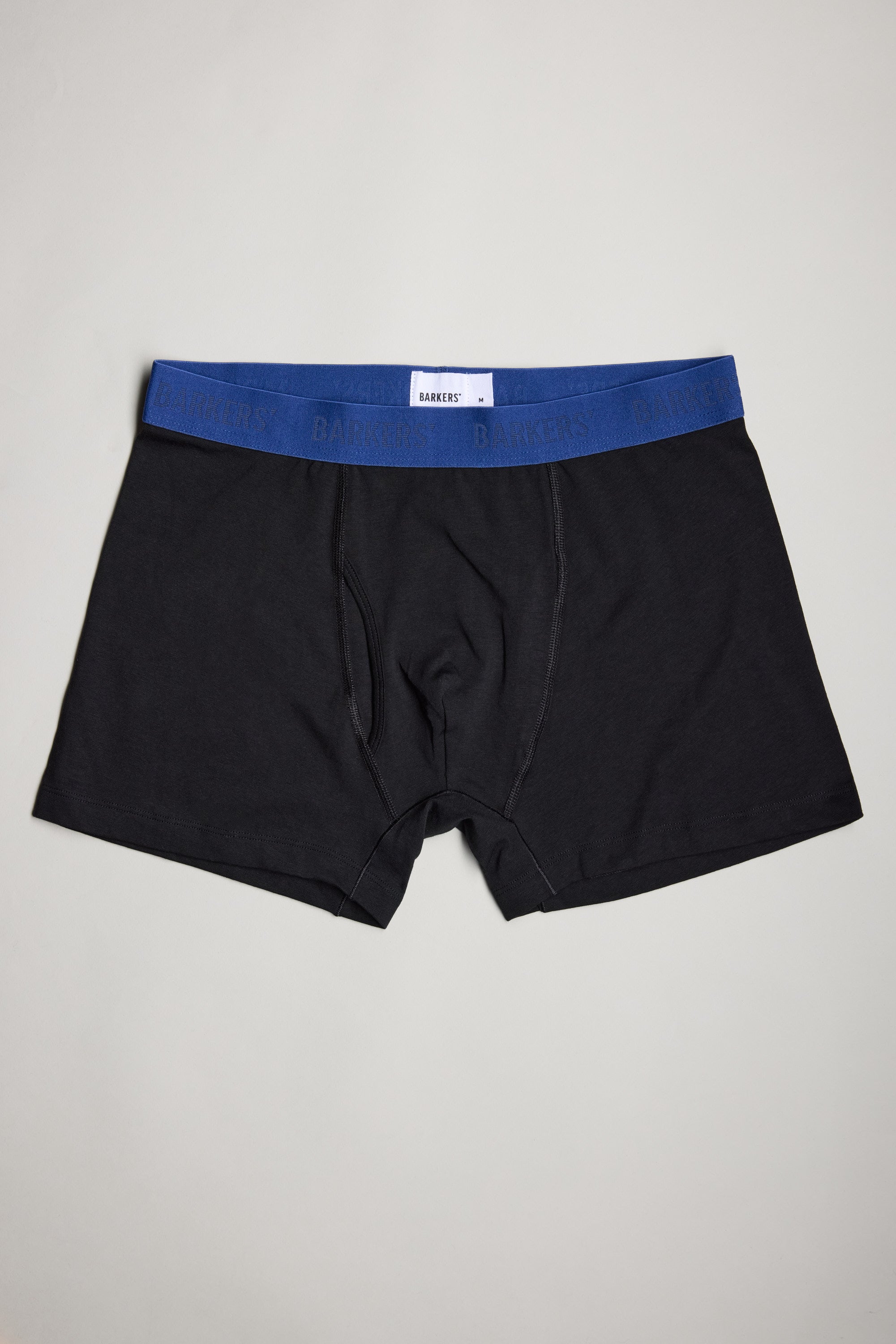 A set of Barkers 3-Pack Organic Trunk boxer briefs in black with a blue elastic waistband, featuring subtle branding, is displayed flat on a light gray surface—an ideal choice for your men’s underwear collection.