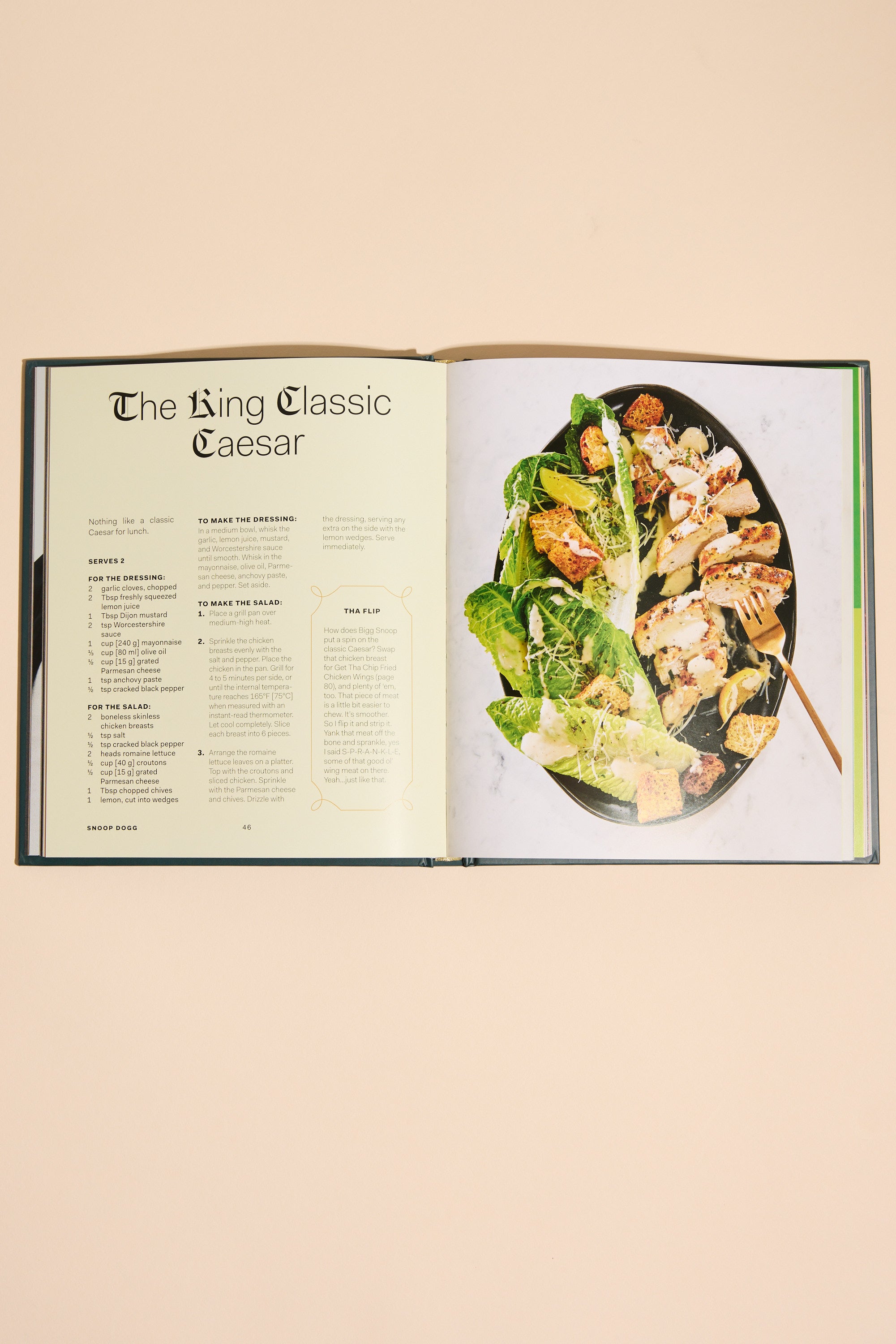 An open copy of "From Crook to Cook" by Other shows a cannabis-free King Classic Caesar recipe on the left and a photo of Caesar salad with lettuce, croutons, and dressing on a black plate with a fork on the right.