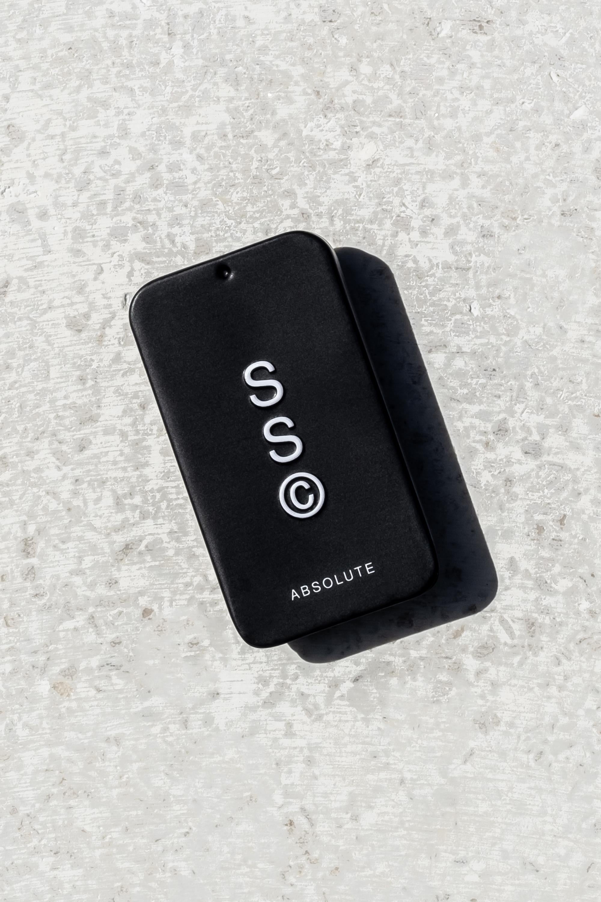 Solid State - Absolute by Solid State is a black, rectangular, pocket-sized cologne with "SSC©" and "ABSOLUTE" printed on it, placed on a textured light gray surface—ideal for those who love Creed Aventus inspired scents.