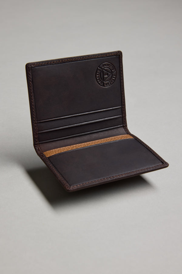 The Barkers Marlin Leather Slim Wallet, shown standing upright on a plain gray surface, features dark brown leather, visible stitching, and a circular embossed logo on the inside upper flap.