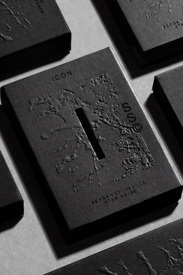 A black rectangular box labeled Solid State - Icon with embossed branch patterns and a central vertical slit. This solid cologne by Solid State features Australian scents: bergamot, vanilla, and star anise on a light background.